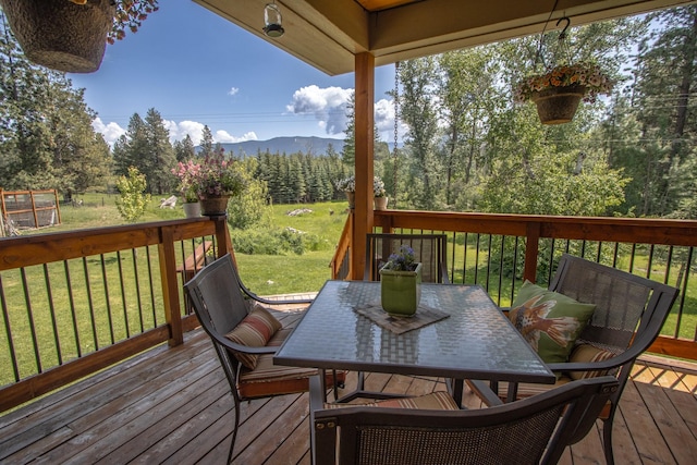 1265 Jellison Rd, Columbia Falls, MT 59912 - wooden terrace with outdoor dining area, a lawn, and a mountain view