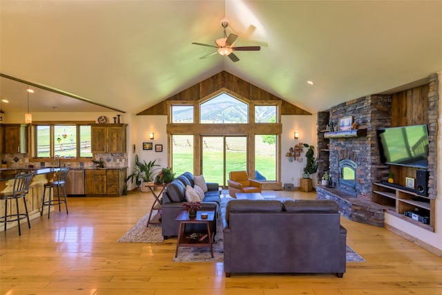 6659 Lamar Trl, Florence, MT 59833 - living area with high vaulted ceiling, ceiling fan, light wood-style flooring, and a stone fireplace