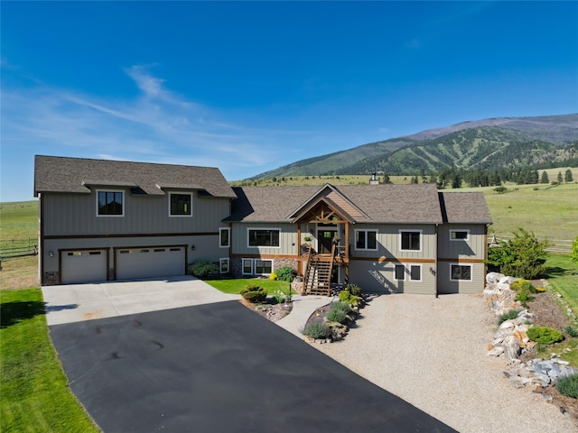 6659 Lamar Trl, Florence, MT 59833 - view of front facade with driveway, a mountain view, an attached garage, roof with shingles, and board and batten siding