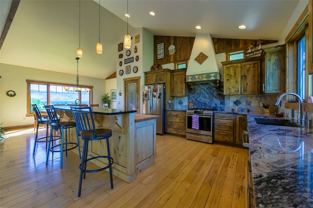 6659 Lamar Trl, Florence, MT 59833 - kitchen with appliances with stainless steel finishes, custom range hood, light wood finished floors, a kitchen bar, and tasteful backsplash