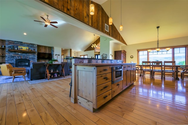 6659 Lamar Trl, Florence, MT 59833 - kitchen featuring stainless steel oven, ceiling fan, light wood-style flooring, decorative light fixtures, and high vaulted ceiling