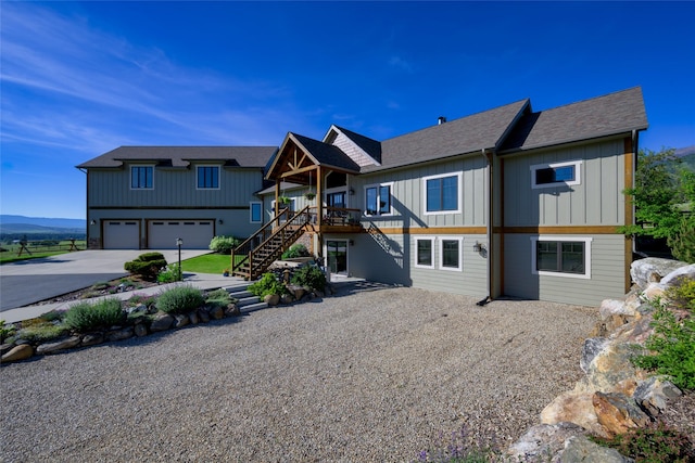 6659 Lamar Trl, Florence, MT 59833 - rear view of property featuring driveway, stairway, board and batten siding, an attached garage, and roof with shingles