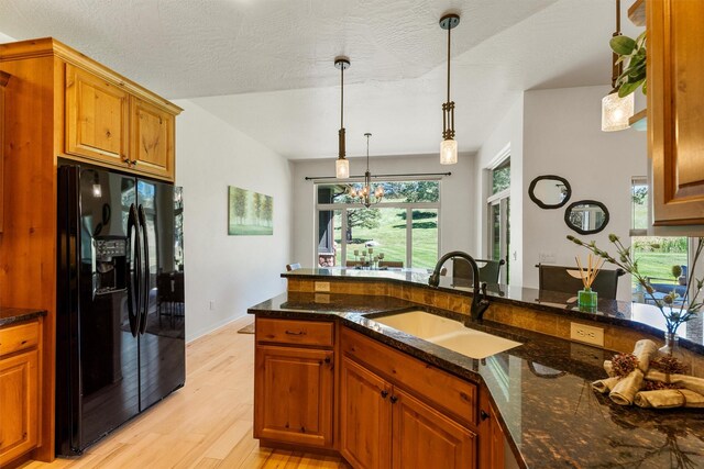720 Anglers Bend Way, Missoula, MT 59802 - kitchen featuring black fridge, a sink, light wood-style floors, dark stone counters, and brown cabinetry