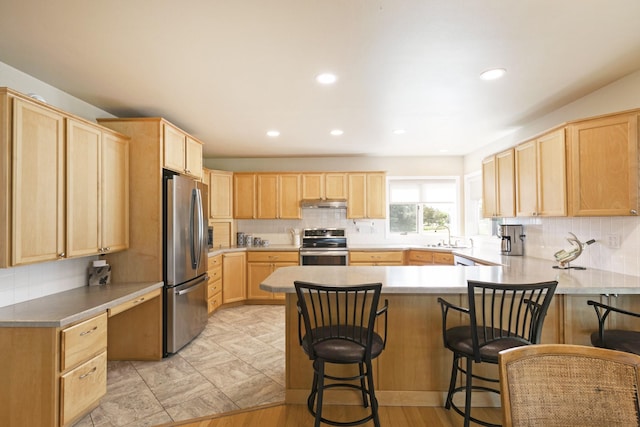 10190 Kona Ranch Rd, Missoula, MT 59808 - kitchen with appliances with stainless steel finishes, light brown cabinetry, under cabinet range hood, backsplash, and a peninsula