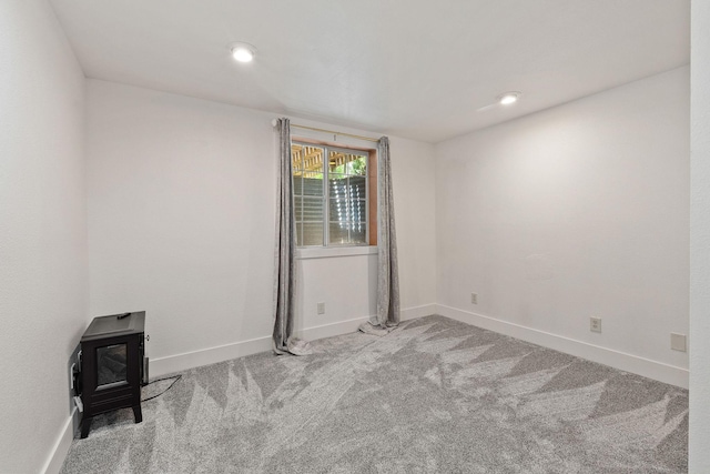 2249 Canvasback Ct, Kalispell, MT 59901 - spare room featuring a wood stove, carpet floors, and baseboards