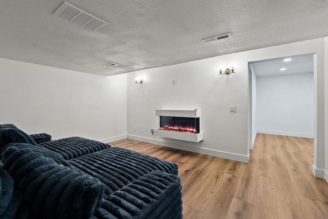 2249 Canvasback Ct, Kalispell, MT 59901 - living room with light wood-style flooring, a textured ceiling, baseboards, and a warm lit fireplace
