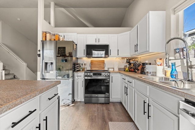 119 Barron Way, Kalispell, MT 59901 - kitchen with stainless steel appliances, vaulted ceiling, white cabinetry, and dark wood-type flooring