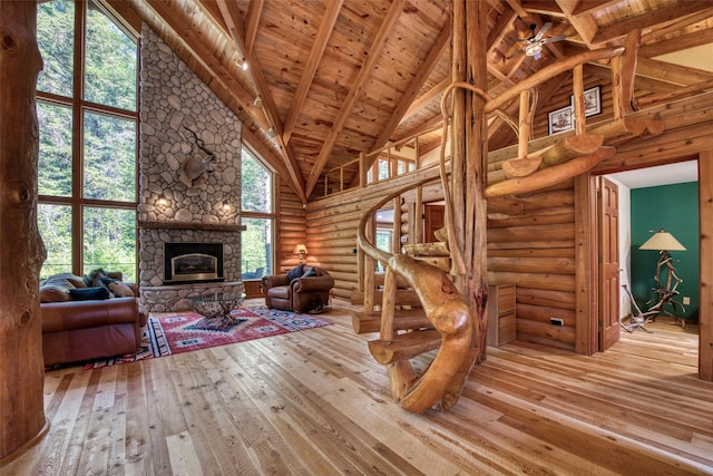 1062 Bear Creek Trl, Victor, MT 59875 - living area featuring high vaulted ceiling, wood-type flooring, log walls, a fireplace, and stairs