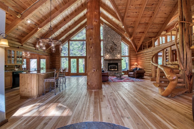 1062 Bear Creek Trl, Victor, MT 59875 - living room with a wooden ceiling with exposed beams, high vaulted ceiling, log walls, light wood-type flooring, and a stone fireplace