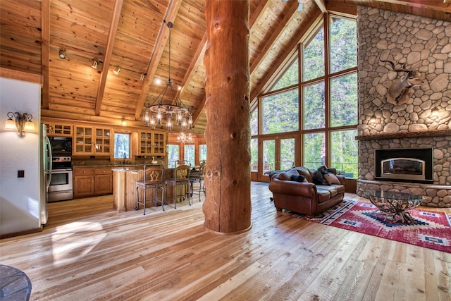 1062 Bear Creek Trl, Victor, MT 59875 - living room featuring high vaulted ceiling, light wood finished floors, a chandelier, a wooden ceiling with exposed beams, and a fireplace