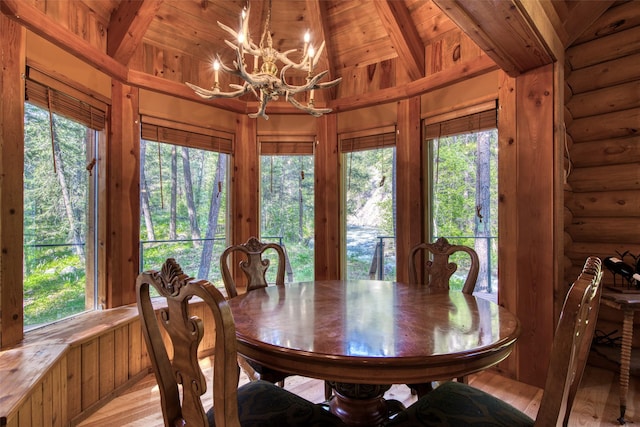 1062 Bear Creek Trl, Victor, MT 59875 - dining area featuring a chandelier, vaulted ceiling, light wood-style floors, and rustic walls