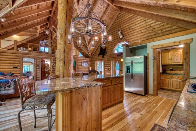 1062 Bear Creek Trl, Victor, MT 59875 - kitchen featuring stainless steel fridge with ice dispenser, log walls, high vaulted ceiling, light wood finished floors, and open floor plan