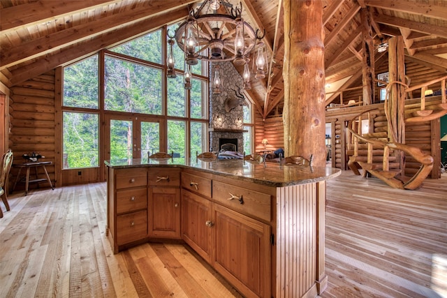 1062 Bear Creek Trl, Victor, MT 59875 - kitchen with high vaulted ceiling, rustic walls, light wood finished floors, a chandelier, and a stone fireplace