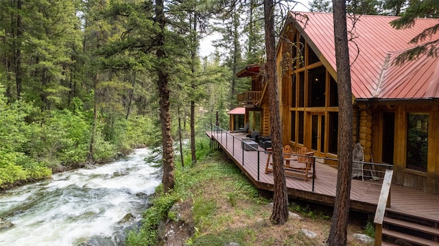 1062 Bear Creek Trl, Victor, MT 59875 - rear view of house with a wooden deck, a view of trees, a metal roof, a balcony, and a standing seam roof
