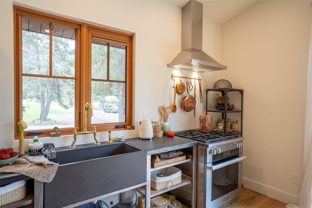 135 Gamma Rd, Hungry Horse, MT 59919 - kitchen with stainless steel gas range oven, ventilation hood, a sink, baseboards, and wood finished floors