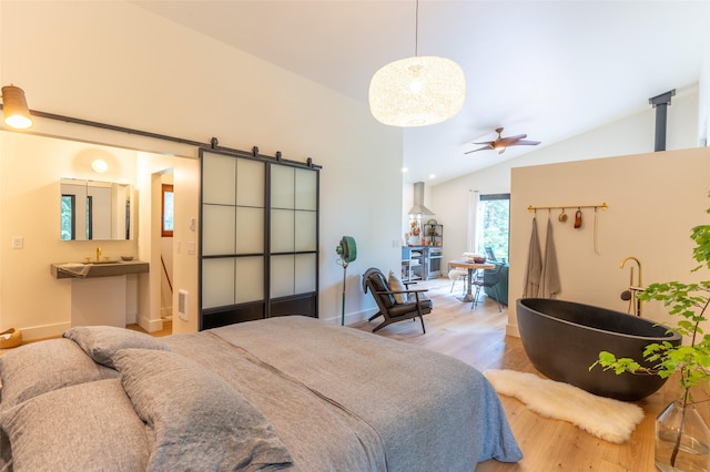 135 Gamma Rd, Hungry Horse, MT 59919 - bedroom featuring wood finished floors, vaulted ceiling, a barn door, a sink, and baseboards