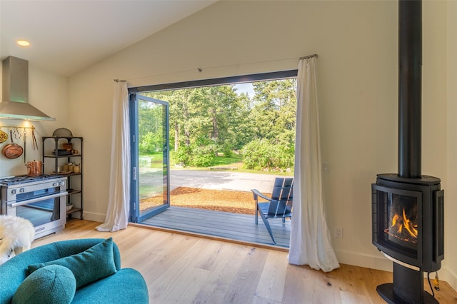 135 Gamma Rd, Hungry Horse, MT 59919 - doorway to outside with a wood stove, wood finished floors, vaulted ceiling, recessed lighting, and baseboards