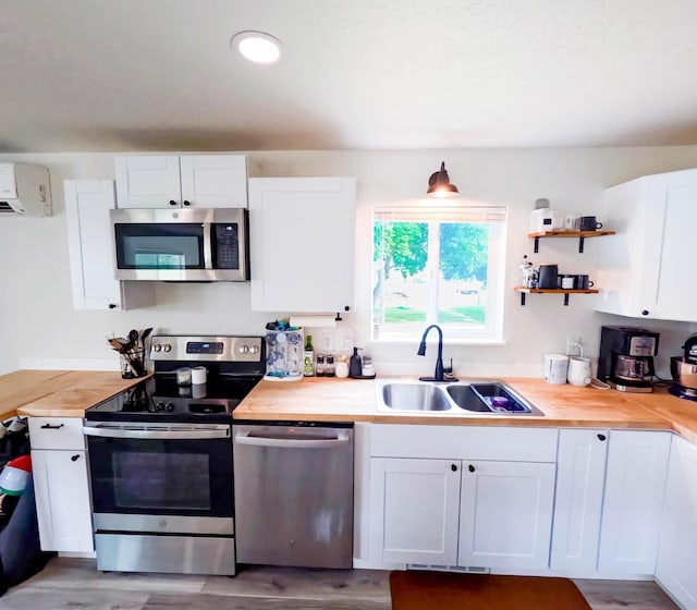 1203 1st St E, Polson, MT 59860 - kitchen with stainless steel appliances, a sink, wood counters, and white cabinetry