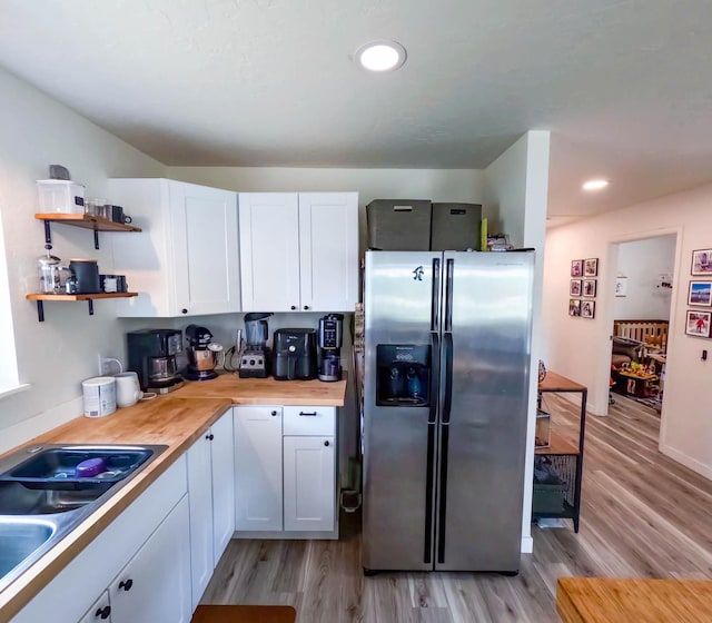1203 1st St E, Polson, MT 59860 - kitchen with stainless steel fridge, a sink, white cabinets, light wood-style floors, and open shelves