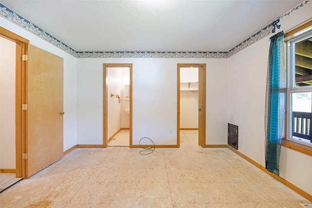1065 Evergreen Dr, Seeley Lake, MT 59868 - unfurnished bedroom featuring baseboards, ensuite bath, and a walk in closet