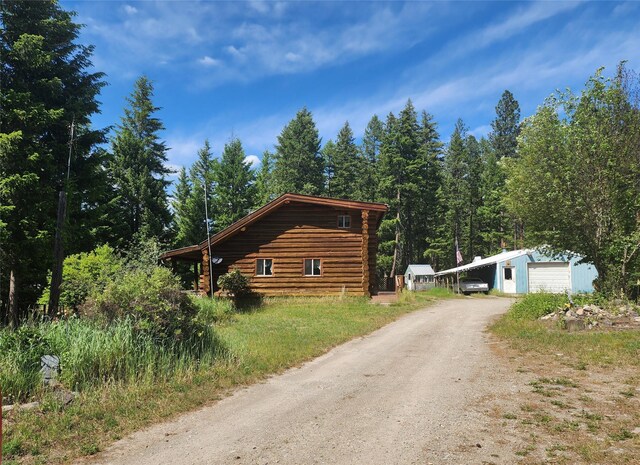 137 Amber Rd, Troy, MT 59935 - view of side of property featuring driveway, log exterior, a detached garage, and an outdoor structure