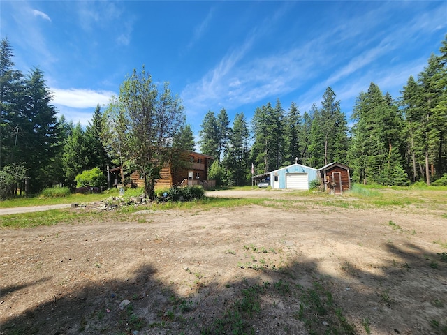 137 Amber Rd, Troy, MT 59935 - view of yard featuring a detached garage, an outdoor structure, a wooded view, and driveway