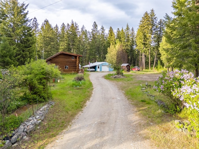 137 Amber Rd, Troy, MT 59935 - cabin featuring a detached garage, a view of trees, dirt driveway, and an outbuilding