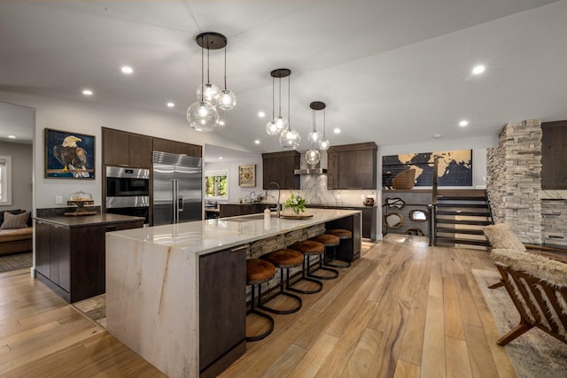 309 Fairway Dr, Whitefish, MT 59937 - kitchen with stainless steel appliances, a large island, dark brown cabinetry, light wood-type flooring, and recessed lighting