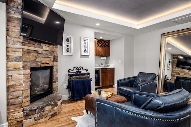 309 Fairway Dr, Whitefish, MT 59937 - living room with a stone fireplace, wine cooler, light wood-type flooring, recessed lighting, and a raised ceiling