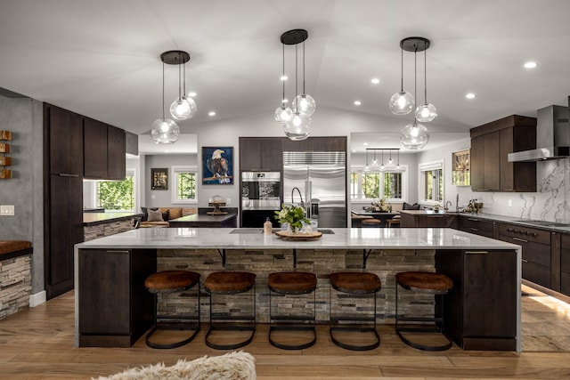 309 Fairway Dr, Whitefish, MT 59937 - kitchen with appliances with stainless steel finishes, wall chimney exhaust hood, modern cabinets, dark brown cabinetry, and a large island with sink