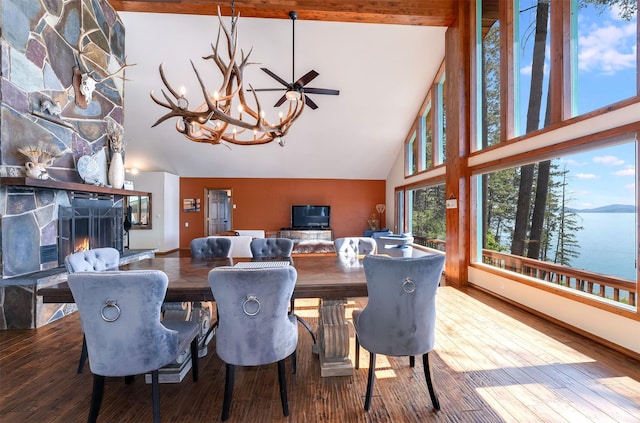 14690 Shore Acres Dr, Bigfork, MT 59911 - dining space with high vaulted ceiling, a stone fireplace, a chandelier, wood finished floors, and beam ceiling