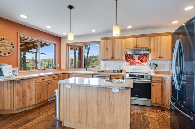 14690 Shore Acres Dr, Bigfork, MT 59911 - kitchen featuring stainless steel appliances, a sink, under cabinet range hood, a kitchen island, and decorative backsplash