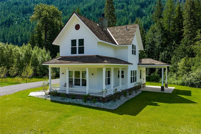 189 Blue Creek Rd, Heron, MT 59844 - view of front of home featuring a wooded view, covered porch, a chimney, and a front yard