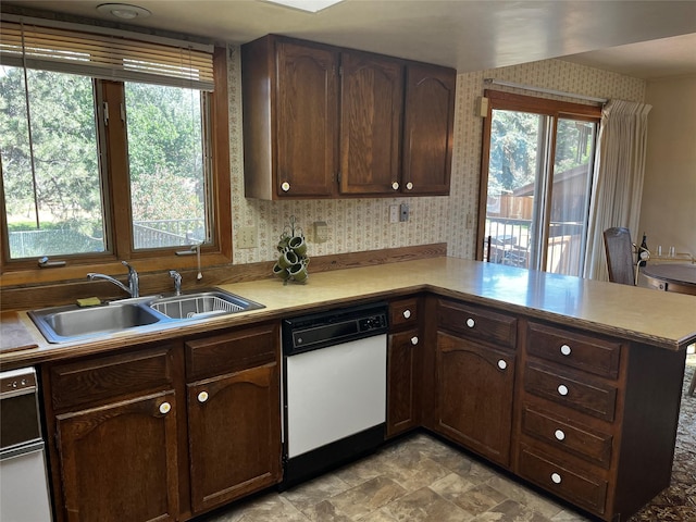 1114 Creek Crossing Rd, Missoula, MT 59802 - kitchen with white dishwasher, a peninsula, a sink, wallpapered walls, and plenty of natural light