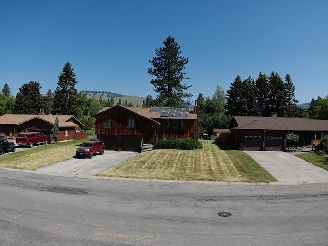 1114 Creek Crossing Rd, Missoula, MT 59802 - view of front of property featuring concrete driveway, roof mounted solar panels, a front yard, and a garage