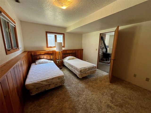 1114 Creek Crossing Rd, Missoula, MT 59802 - bedroom with carpet flooring, a textured ceiling, and a wood stove