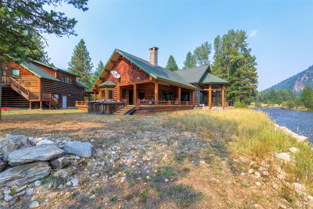 6900 Nez Perce Rd, Darby, MT 59829 - rear view of property with a hot tub, a chimney, stairway, a water view, and a porch