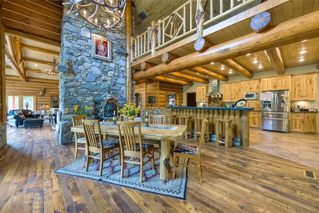 6900 Nez Perce Rd, Darby, MT 59829 - dining room with a chandelier, hardwood / wood-style floors, a stone fireplace, wooden ceiling with exposed beams, and a towering ceiling