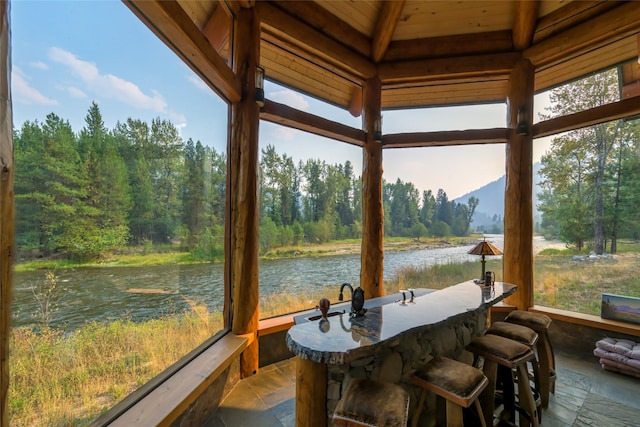 6900 Nez Perce Rd, Darby, MT 59829 - sunroom featuring a water view, stone tile floors, wood ceiling, and a wooded view
