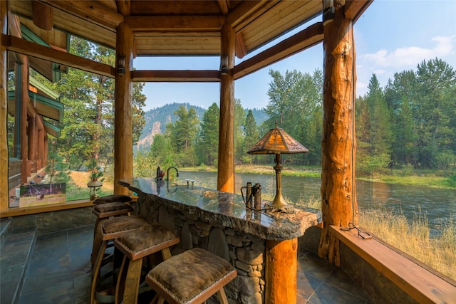 6900 Nez Perce Rd, Darby, MT 59829 - sunroom / solarium with stone tile flooring, bar with sink, a wooded view, and a water view
