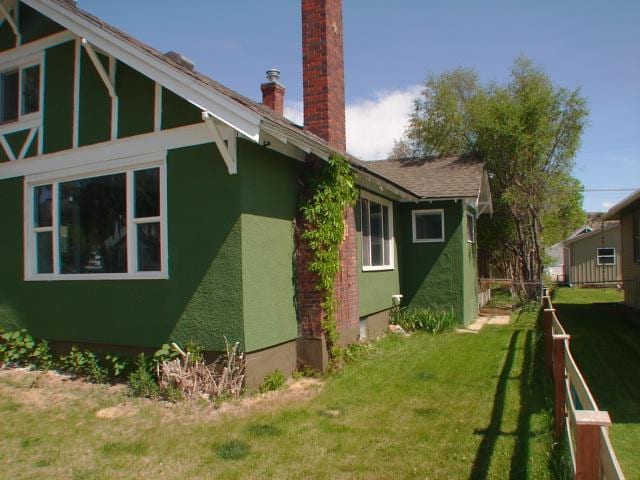 808 W 4th St, Anaconda, MT 59711 - view of home's exterior featuring a chimney, stucco siding, and a lawn
