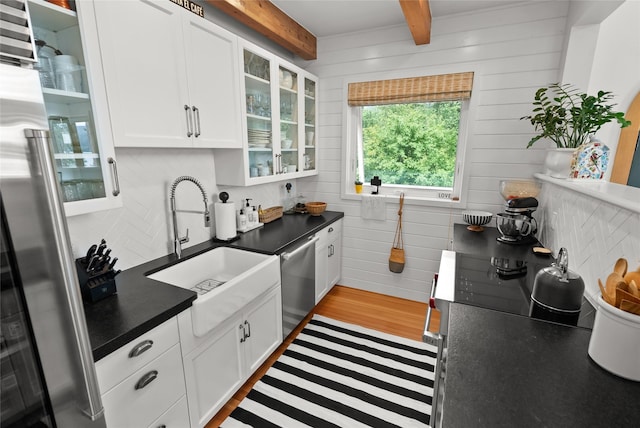 14833 Sunburst Dr, Bigfork, MT 59911 - kitchen with stainless steel appliances, dark countertops, white cabinetry, decorative backsplash, and beamed ceiling