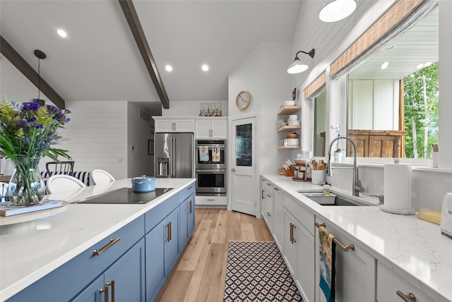 14833 Sunburst Dr, Bigfork, MT 59911 - kitchen featuring stainless steel appliances, blue cabinets, open shelves, beamed ceiling, and light wood-style floors