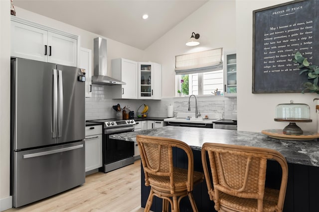 14833 Sunburst Dr, Bigfork, MT 59911 - kitchen featuring stainless steel appliances, wall chimney range hood, lofted ceiling, tasteful backsplash, and glass insert cabinets