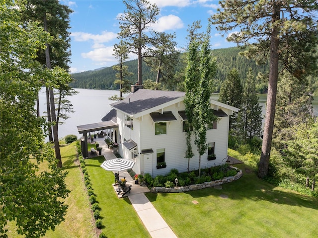 14833 Sunburst Dr, Bigfork, MT 59911 - view of front facade featuring a view of trees, a front lawn, a water view, and roof with shingles