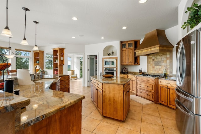 5959 Hayes Creek Rd, Missoula, MT 59804 - kitchen with stainless steel appliances, a sink, a spacious island, custom exhaust hood, and brown cabinets