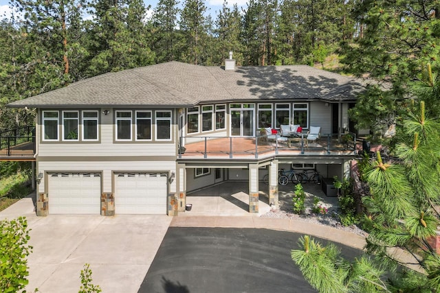 5959 Hayes Creek Rd, Missoula, MT 59804 - view of front facade featuring driveway, a garage, roof with shingles, a wooden deck, and stone siding