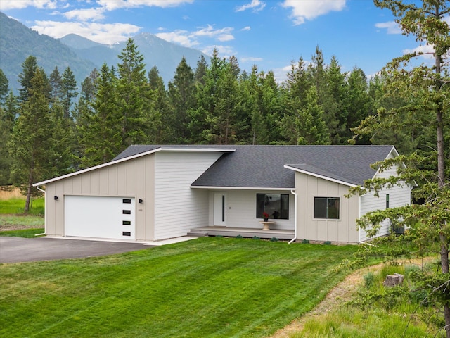 100 Bench Run, Columbia Falls, MT 59912 - mid-century modern home with an attached garage, asphalt driveway, roof with shingles, and board and batten siding