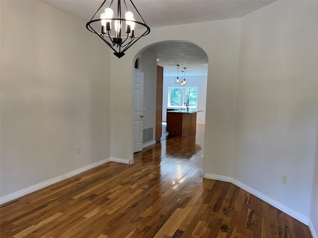 638 Trestle Creek Dr, Saint Regis, MT 59866 - unfurnished dining area featuring a chandelier, arched walkways, wood finished floors, and baseboards