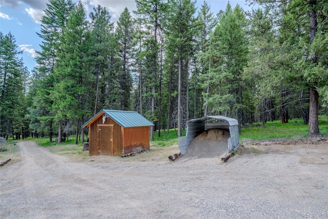 104 Swede Gulch Rd, Libby, MT 59923 - view of shed with a carport, dirt driveway, and a forest view